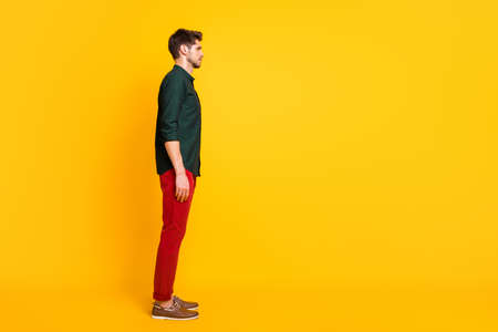 Full length body size photo of candid pensive indifferent man standing straight side profile looking into empty space isolated over bright color backgroundの写真素材