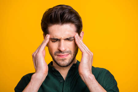 Close up photo of suffering man in pain with bristle shutting his eyes in a fit of hurtful illness isolated over yellow vibrant color backgroundの写真素材