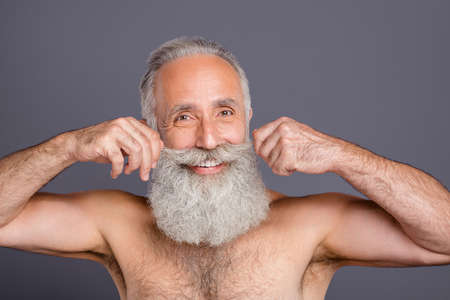 Photo of cheerful positive confident man pleased about the work of hairstylist having got new mustaches isolated grey color backgroundの写真素材