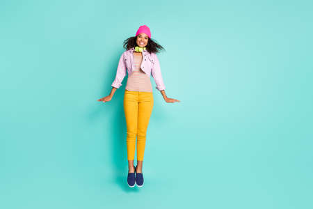 Full length body size photo style of cheerful positive cute nice pretty, girlfriend jumping up wearing yellow pants striped t-shirt flying like rocket smiling toothily isolated pastel color teal backgroundの写真素材