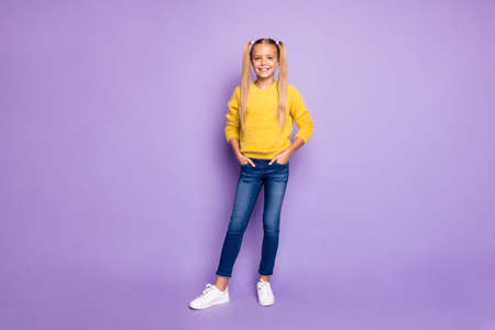 Full length photo of positive cheerful kid enjoy rest relax put hands denim jeans stand over violet color backgroundの写真素材