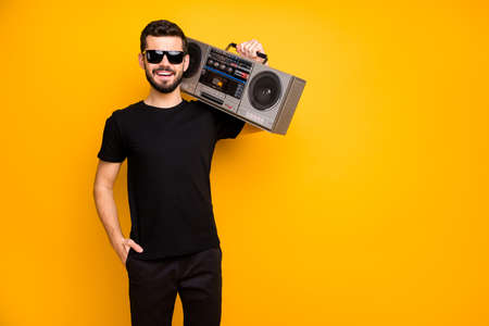 Portrait of cool charming positive guy hold boom box on his shoulder want listen vintage music on journey wear black friday clothes isolated over bright color backgroundの写真素材