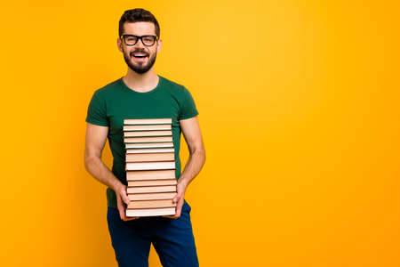 Portrait of positive guy high school student hold pile stack paper book ready learn prepare exam wear good looking outfit isolated over yellow color backgroundの写真素材