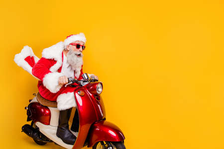 Profile side photo of shocked crazy santa claus ride fast his scooter hurry on x-mas party wear shirt suspenders drive copyspace isolated over yellow color backgroundの写真素材