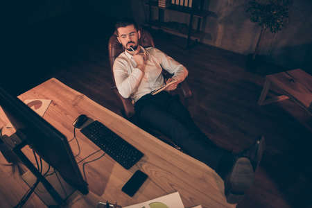 Top above high angle view photo of thoughtful concentrated entrepreneur looking pensively into screen in search of useful valuable information with legs on tableの写真素材