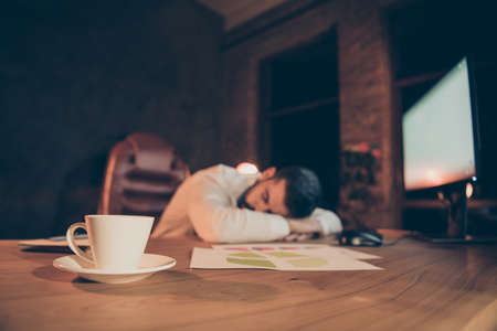 Overworked workaholic man sleep on desk feel tired on night shifts want rest at night work with...