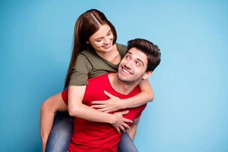 Portrait of positive romantic two dreamy couple man hug his wife spouse piggy-back wear casual style outfit isolated over blue color backgroundの写真素材