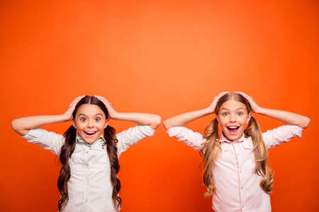 Wow autumn bargains. Portrait of funky crazy two kids hear incredible news scream omg touch hands head wear white shirts outfit isolated over orange color backgroundの写真素材