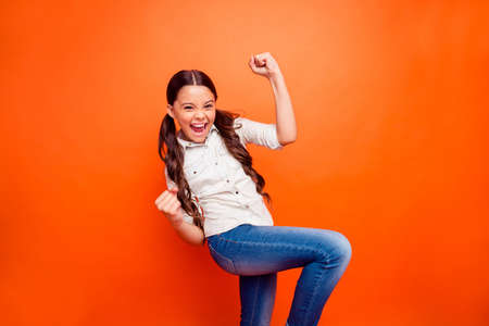 Portrait of excited ecstatic little girl win sport contest shout yeah raise fists feel content wear...