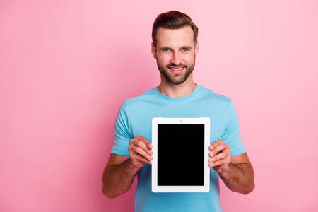 Photo of cheerful positive cheerful man smiling toothily holding tablet, demomstrating you its...
