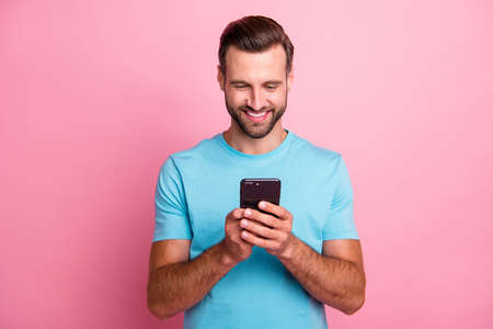 Photo of trendy cheerful positive smm manager browsing through telephone in search of ways to update...