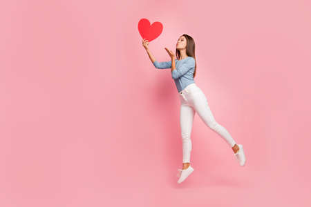 Full length body size side brown haired profile photo of cheerful positive cute pretty nice tender girl sending air kiss to heart held isolated pastel color backgroundの写真素材