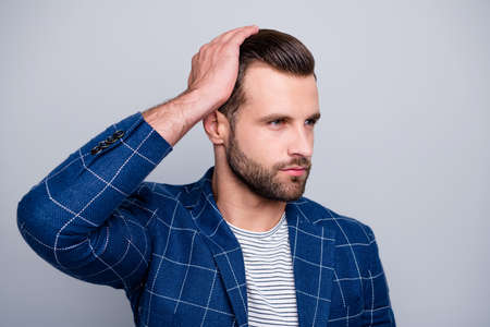 Close up photo of serious confident man applying balm on his hair to look better with bristle on...