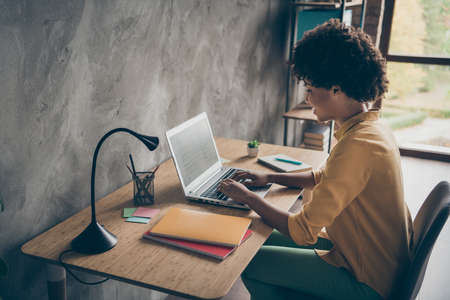 Profile side photo of focused afro american girl smm worker use laptop read startup information work presentation sit table in office loft workstationの写真素材