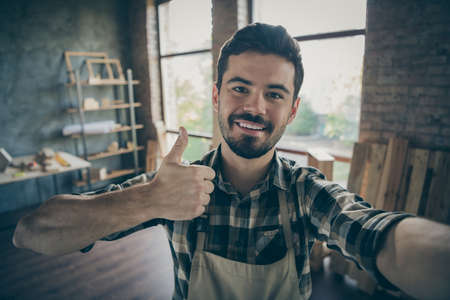 Closeup photo of handsome guy master raising thumb up making selfies in new own wooden business...