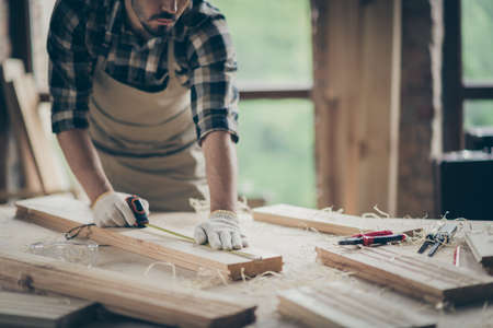 Cropped view of his he nice attractive focused experienced professional guy expert measuring plank board creating house project start-up at modern industrial loft style interior indoorsの写真素材