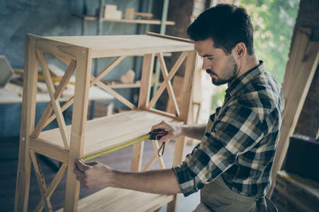 Profile photo of handsome guy building book shelf modern design handmade wooden industry measuring length distance between departments workshop indoorsの写真素材