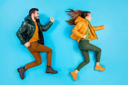 Top above high angle view full length body size photo of casual cute pretty couple of people running towards sale shop while lying smiling toothily isolated pastel color blue backgroundの写真素材