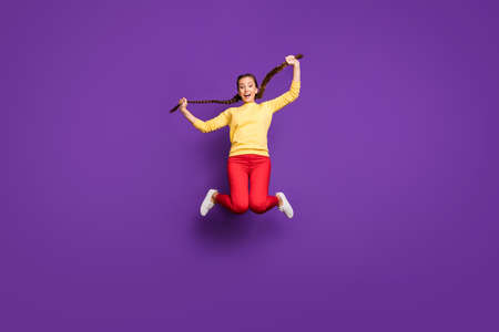 Full body photo of crazy youngster lady jumping high spending best free time holding long braids...