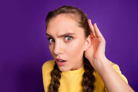 Closeup photo of funny lady long braids holding arm near ear listening fresh rumours chatterbox person wear casual yellow jumper isolated purple color backgroundの写真素材