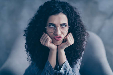 Close-up portrait of her she nice-looking attractive discontent naughty mad irritated bored wavy-haired girl sitting in chair waiting grimacing isolated over gray concrete wall backgroundの写真素材