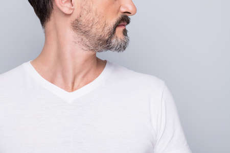 Closeup cropped photo of attractive aged man seriously looking side empty space mature wrinkles appearance showing nice beard wear white t-shirt isolated grey color backgroundの写真素材