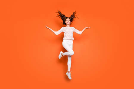 Full size photo of cheerful positive girl dream dreamy hold hand show her wavy luxury haircut jump wear lace knitted outfit sneakers isolated over orange color backgroundの写真素材
