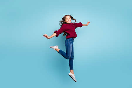 Full length body size side profile photo of cheerful positive smiling toothy beaming girl dancing like ballerina curly wavy jumping isolated vivid blue color backgroundの写真素材