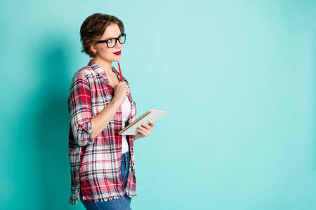 Portrait of interested inspired high school girl want write copybook diary note think thoughts dream ponder wear stylish outfit denim jeans isolated over turquoise color backgroundの写真素材