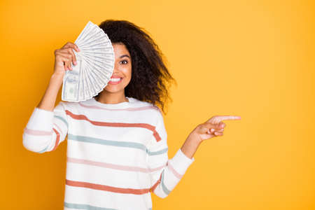 Portrait of nice attractive cheerful cheery wavy-haired girl wearing sweater pullover hiding half face behind budget pointing aside look isolated on bright vivid shine vibrant yellow color backgroundの写真素材