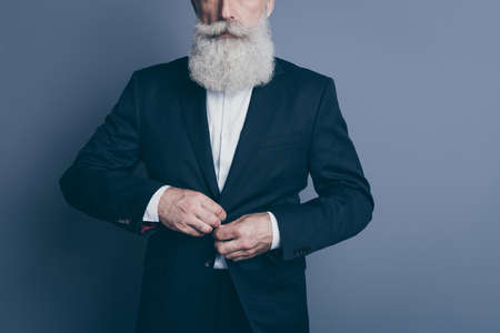 Cropped view portrait of his he nice attractive chic classy calm gray-haired, man wearing tux fastening button wearing formalwear isolated over dark grey pastel color backgroundの写真素材