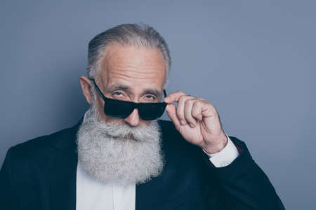 Close-up portrait of his he nice attractive chic classy brutal arrogant serious gray-haired man putting of specs looking at you isolated over dark grey pastel color backgroundの写真素材