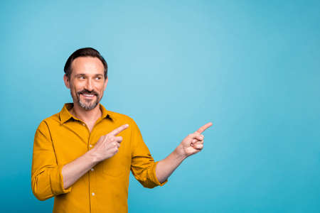 Portrait of positive cheerful man point index finger copyspace indicate sales discounts promotion...