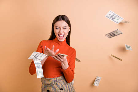 Portrait of her she nice attractive lovely pretty cool cheerful cheery confident straight-haired girl throwing money away isolated over beige pastel color backgroundの写真素材