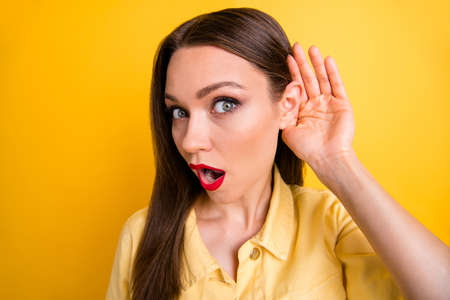 Photo of astonished woman expressing fear on her face with mouth open eavesdropping with palm near...