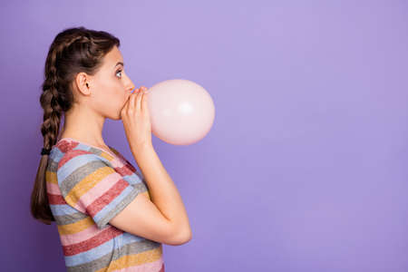 Profile side photo of amazed girl inflate baloon for woman day celebration look copyspace incredible news feel impressed wear millennial clothes isolated purple color backgroundの写真素材