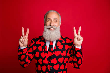 Closeup photo of funky aged attractive man amour cupid role showing v-sign symbols greets party people wear hipster hearts pattern suit costume tie isolated red color backgroundの写真素材