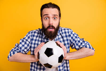 Close-up portrait of his he nice attractive worried bearded guy fan wearing checked shirt holding in hands ball isolated over bright vivid shine vibrant yellow color backgroundの写真素材