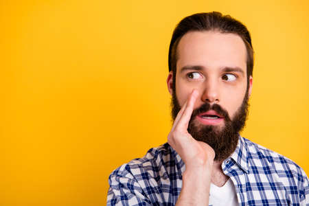Close-up portrait of his he nice attractive worried confused bearded guy in checked shirt saying big secret isolated over bright vivid shine vibrant yellow color backgroundの写真素材