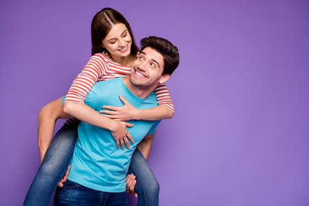 Photo of two funky carefree people guy carrying lady piggyback look eyes cheerful free time adventures wear casual stylish blue striped t-shirts jeans isolated purple color backgroundの写真素材