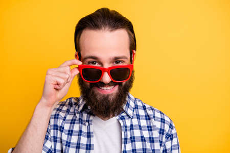 Close-up portrait of his he nice attractive trendy confident cheerful cheery friendly bearded guy wearing checked shirt touching specs isolated over bright vivid shine vibrant yellow color backgroundの写真素材