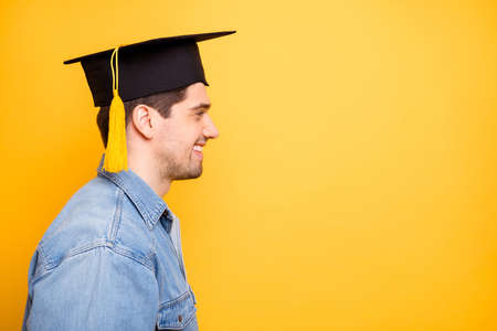 Close-up profile side view portrait of his he nice attractive cheerful cheery content guy wearing cap getting degree specialist scientist isolated on bright vivid shine vibrant yellow color backgroundの写真素材