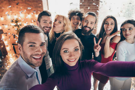 Self portrait of cheerful positive ecstatic overjoyed people showing v-sign amazed surprised smiling toothily loving couples dressed well in raining confettiの写真素材