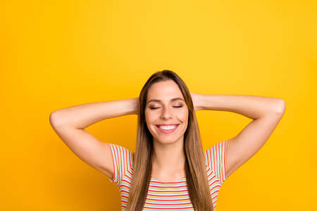 Photo of pretty positive lady resting first summer weekend lying beach eyes closed dreamy mood hands behind head wear casual striped t-shirt isolated yellow color backgroundの写真素材