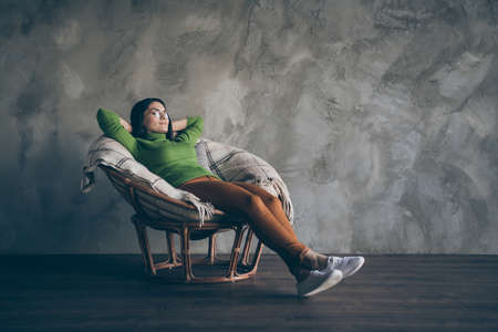 Full length body size photo of cheerful business lady lying in rest in armchair looking far out window in orange pants isolated grey color wall concrete backgroundの写真素材