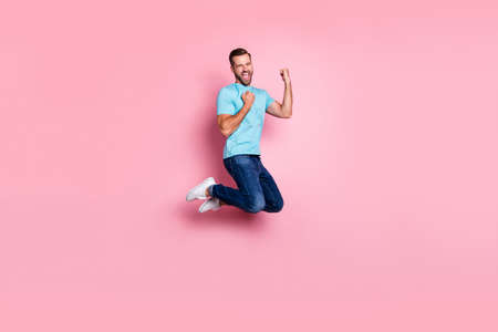 Full length body size profile side photo of cheerful screaming ecstatic man rejoicing in victory his team in jeans denim jumping isolated pastel color backgroundの写真素材