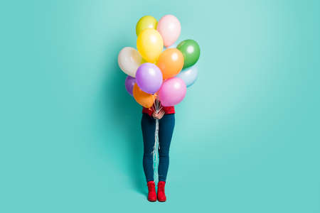 Guess who. Full length photo of hidden lady holding many colorful air balloons making surprise visit wear casual red coat pants boots isolated teal color backgroundの写真素材