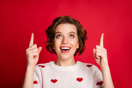 Close-up portrait of her she nice attractive lovely cute cheerful cheery glad girl pointing up surprise gift present solution isolated over bright vivid shine vibrant red color backgroundの写真素材