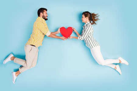 Top view above high angle flat lay flatlay lie concept full length body size view of attractive cheerful couple holding heart isolated on bright vivid shine vibrant blue turquoise color backgroundの写真素材