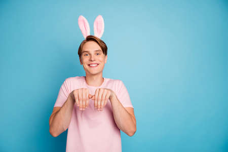 Photo of nice young guy funny good mood playing childish games bunny ears headband on head easter...